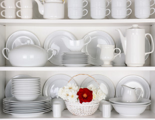 White Plates in Cupboard With a Basket of Roses
