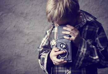 Child blond boy with Vintage photo film camera photographing outside
