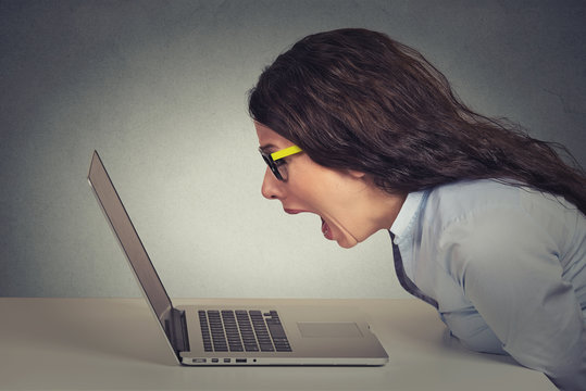 Angry furious businesswoman working on computer, screaming