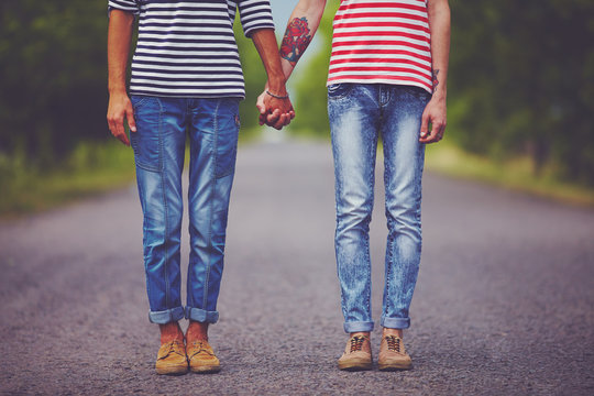 young male couple holding hands standing on their way together