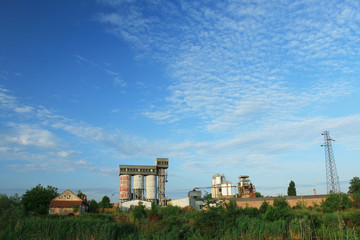 Fototapeta na wymiar Old factory with silo tanks for corn near river