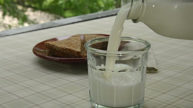 Pouring a glass of milk on a patio
