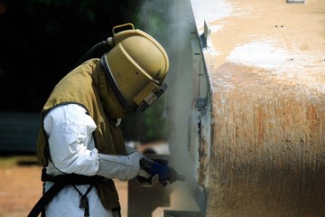 Worker is remove paint by air pressure sand blasting 