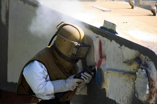 Worker is remove paint by air pressure sand blasting 