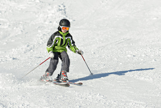 The boy in a green jacket on skis in mountains