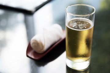 Glass of beer and refreshment towel on table