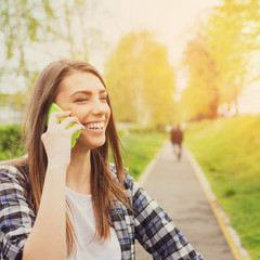 Happy young woman talking on the phone in park