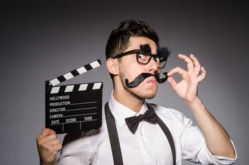 Young man with false moustache holding clapperboard isolated on