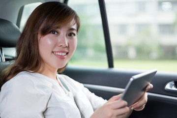 Beautiful asian woman using digital tablet in car