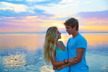 Fototapeta na wymiar Blond young couple hug in sunset sea lake happy