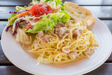 Spaghetti pasta with ham and cream sauce with salad and bread.