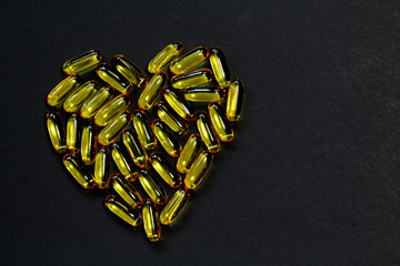 Fish oil omega-3 capsules in heart shape with black background