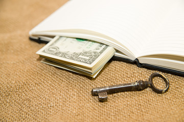 Opened notebook, key and money on the old tissue