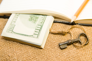 Opened notebook, pencil, key and money on the old tissue