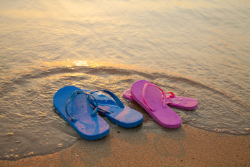 Fototapeta na wymiar Romantic beach scene. Female and male flip flpp sandals on the beach