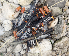many sausage cooking in the fire at summer camp