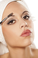 a beautiful young woman comb her eyebrow