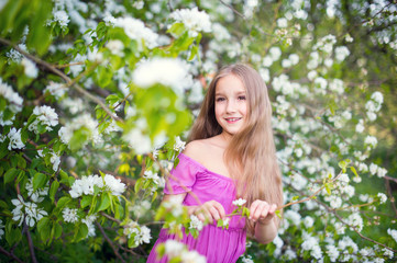 Naklejka premium Beautiful toddler girl in pink dress stay in blossom flowers 