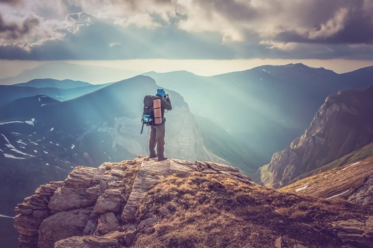 Young Man Standing On A Rock And Looking At A Beautiful Mountain