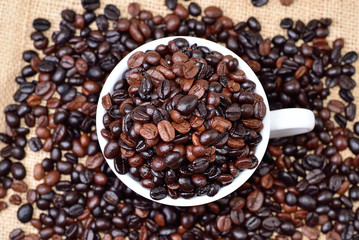 Cup full of coffee beans on the cloth sack
