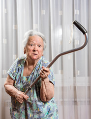 Old angry woman threatening with a cane