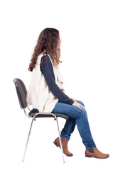back view of young beautiful  woman sitting on chair