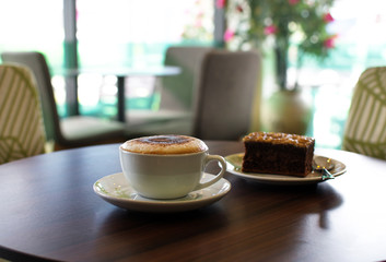 Cup of coffee and a cake on the table in cafe