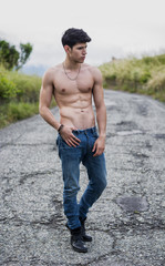 Shirtless muscular young man walking on rural road