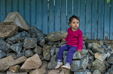 Obraz na płótnie Canvas portrait of cute little girl sitting on rocks