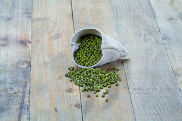 Mung beans in sack on vintage wooden boards