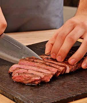 Cortando carne de ternera con un cuchillo,rebanabdo bistec a la Parrilla