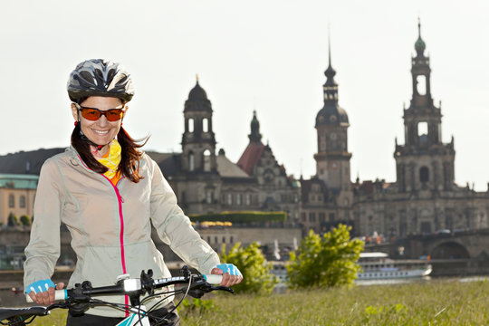 Adult attractive female cyclist posing against the background of