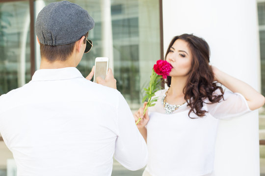 Boy taking photo of his girlfriend on phone camera