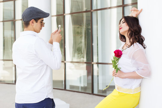 Boy taking photo of his pretty girlfriend on phone camera