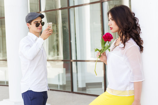 Boy taking photo of his beautiful girlfriend on phone camera