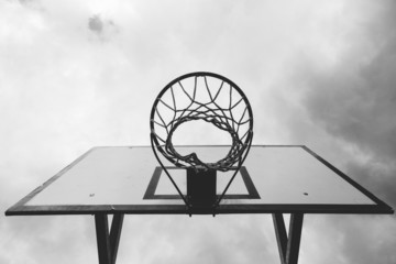 bottom view of the basketball hoop, with sky background, black and white