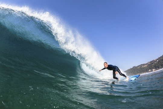 Surfing Surfer  rides Inside hollow blue crashing ocean wave  closeup swimming photo