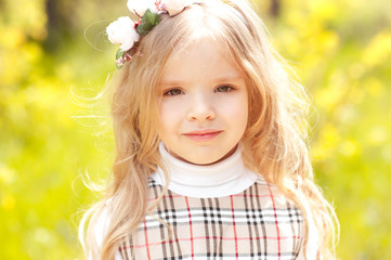 Smiling cute kid girl 3-4 year old wearing floral wreath over green nature background. Looking at camera. Childhood. Summer time. 