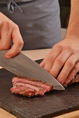 Cortando carne de ternera con un cuchillo,rebanabdo bistec a la Parrilla.
