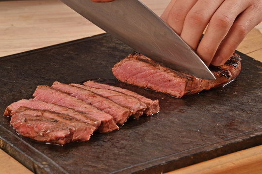 Cortando carne de ternera con un cuchillo,rebanabdo bistec a la Parrilla.