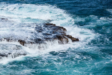 Raging sea flows over lave rocks on shore line