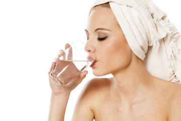 woman with a towel on her head drinking water from a glass 
