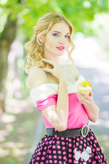 Portrait of a beautiful young blonde woman with long hair on nature. A girl holding a cake with fruit. Soft focus