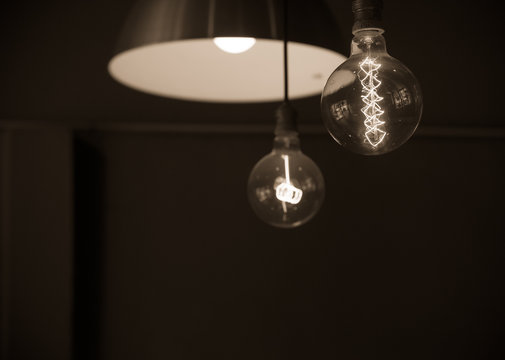 Hanged lamps  focused on light bulb in dark room  in sepia tone