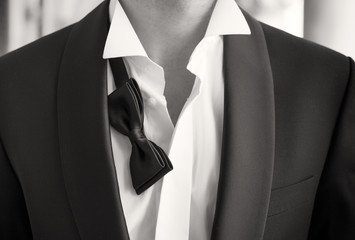 Close-up photo of man in tuxedo with open shirt and loose bow tie