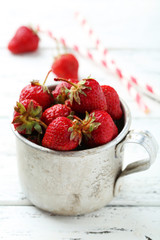 Strawberries berry in cup on white wooden background