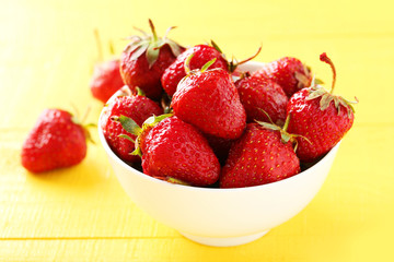Strawberries berry in bowl on yellow wooden background