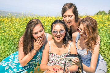 Multiracial girlfriends at countryside picnic watching photos