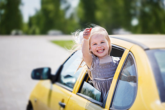 Llittle Smiling Girl Is Sticking Her Head Out The Car Window And