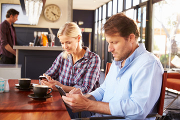 Man and woman using smart phones at coffee shop